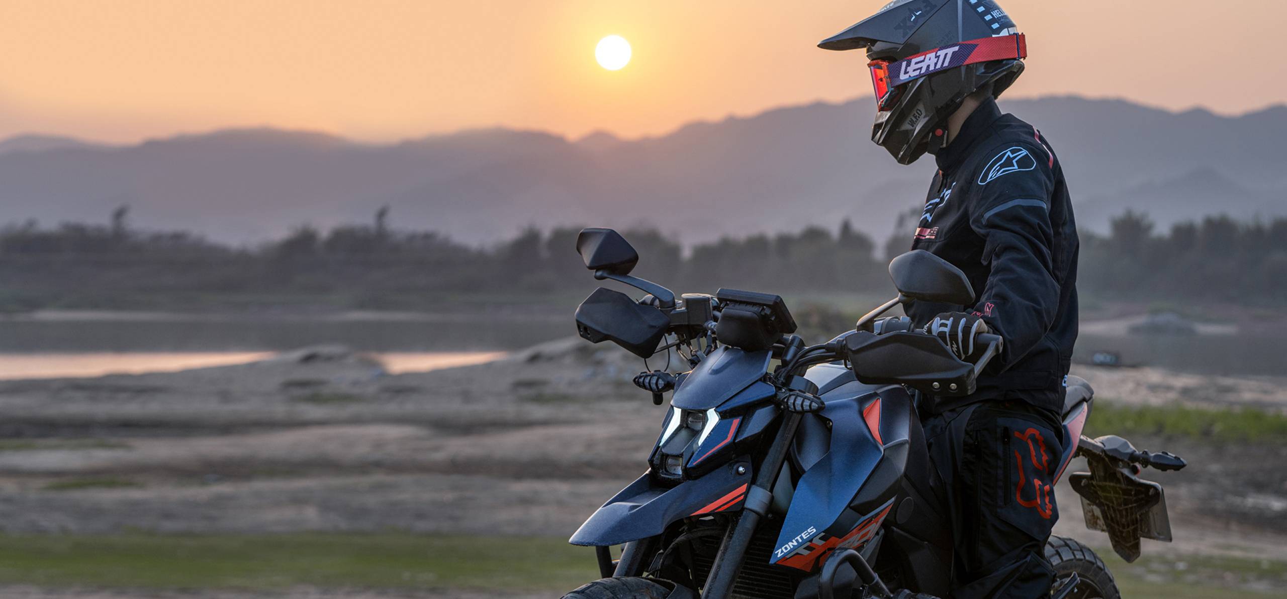 Zontes Moto Tigre Argentina - Moto 200U sobre terreno junto al río durante el atardecer.